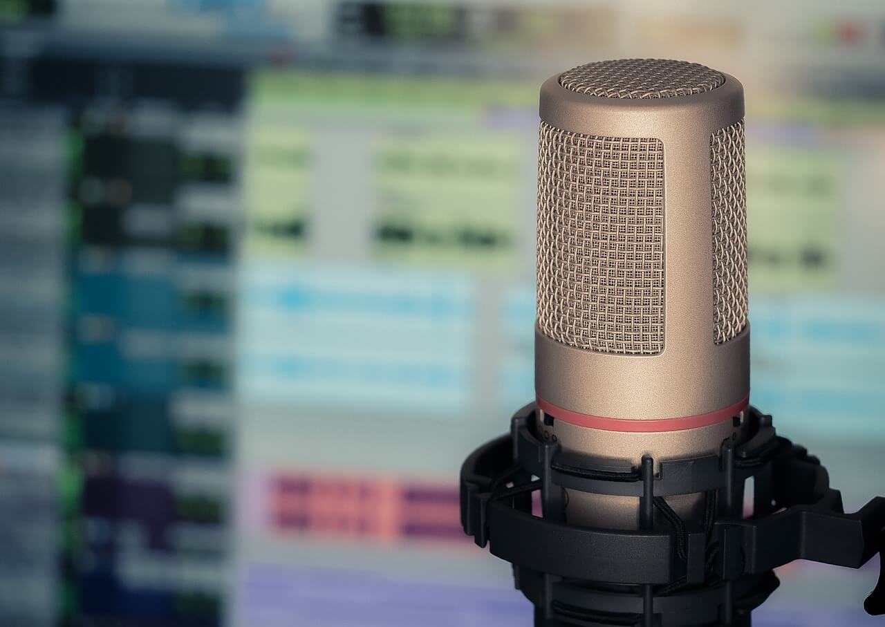 Imagen de un micrófono de podcast delante de una pantalla de ordenador
